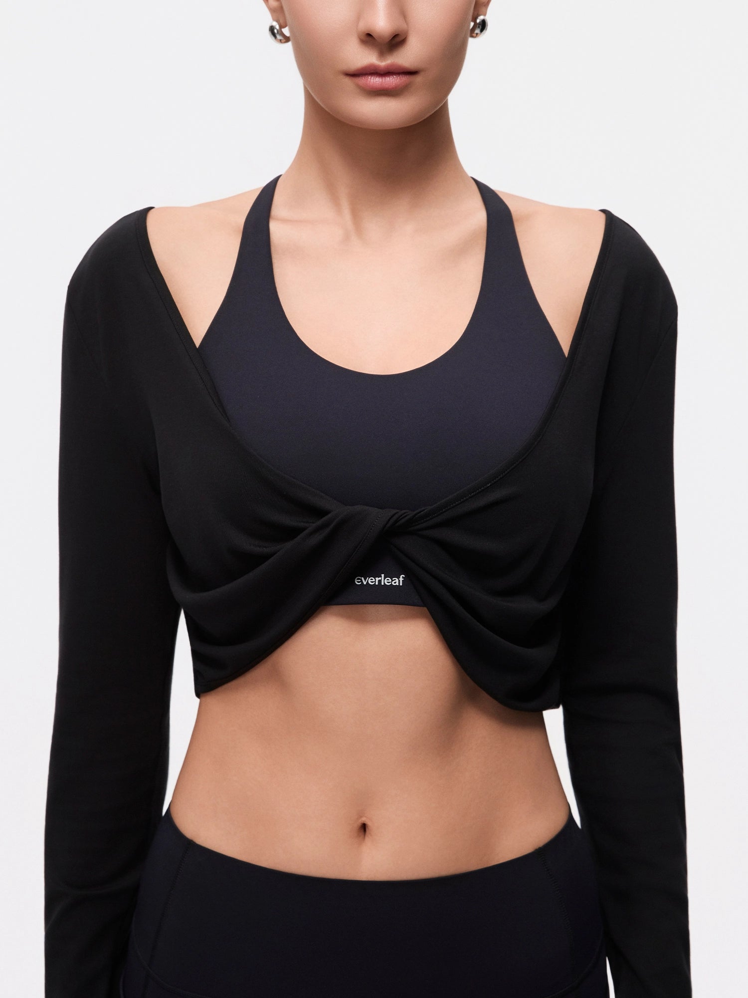 Image of Model wearing the Ebony Black Reversible Ballet Twist Cardigan, half-body front twist detail view.