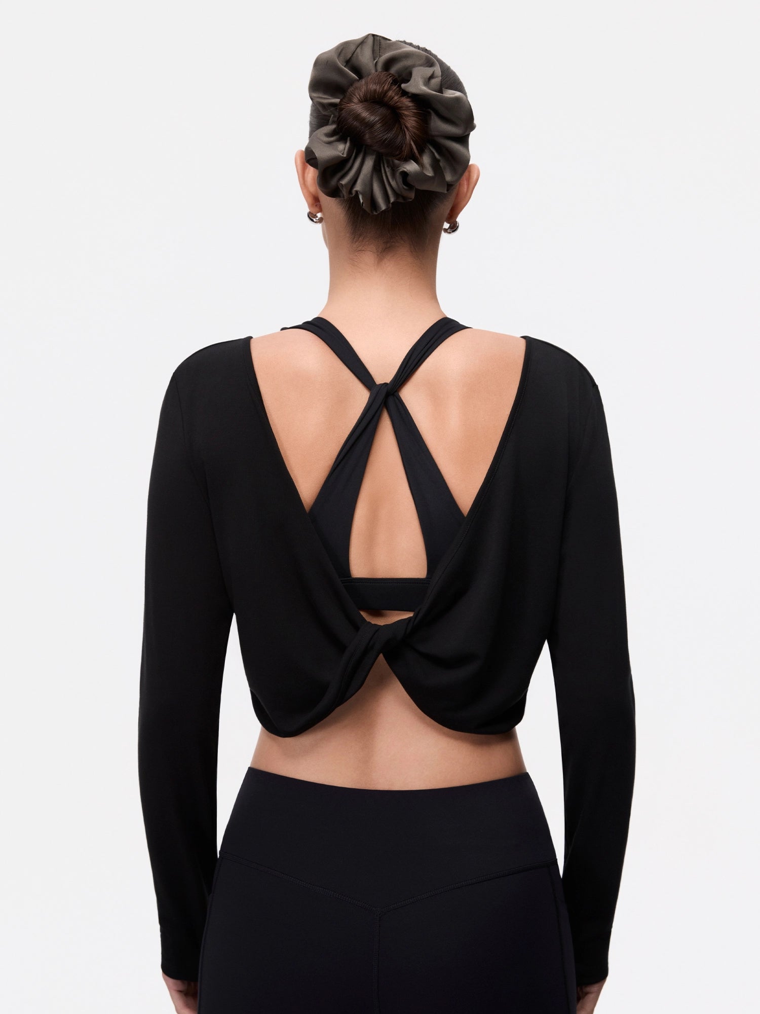 Image of Model wearing the Ebony Black Reversible Ballet Twist Cardigan, half-body back twist detail view.