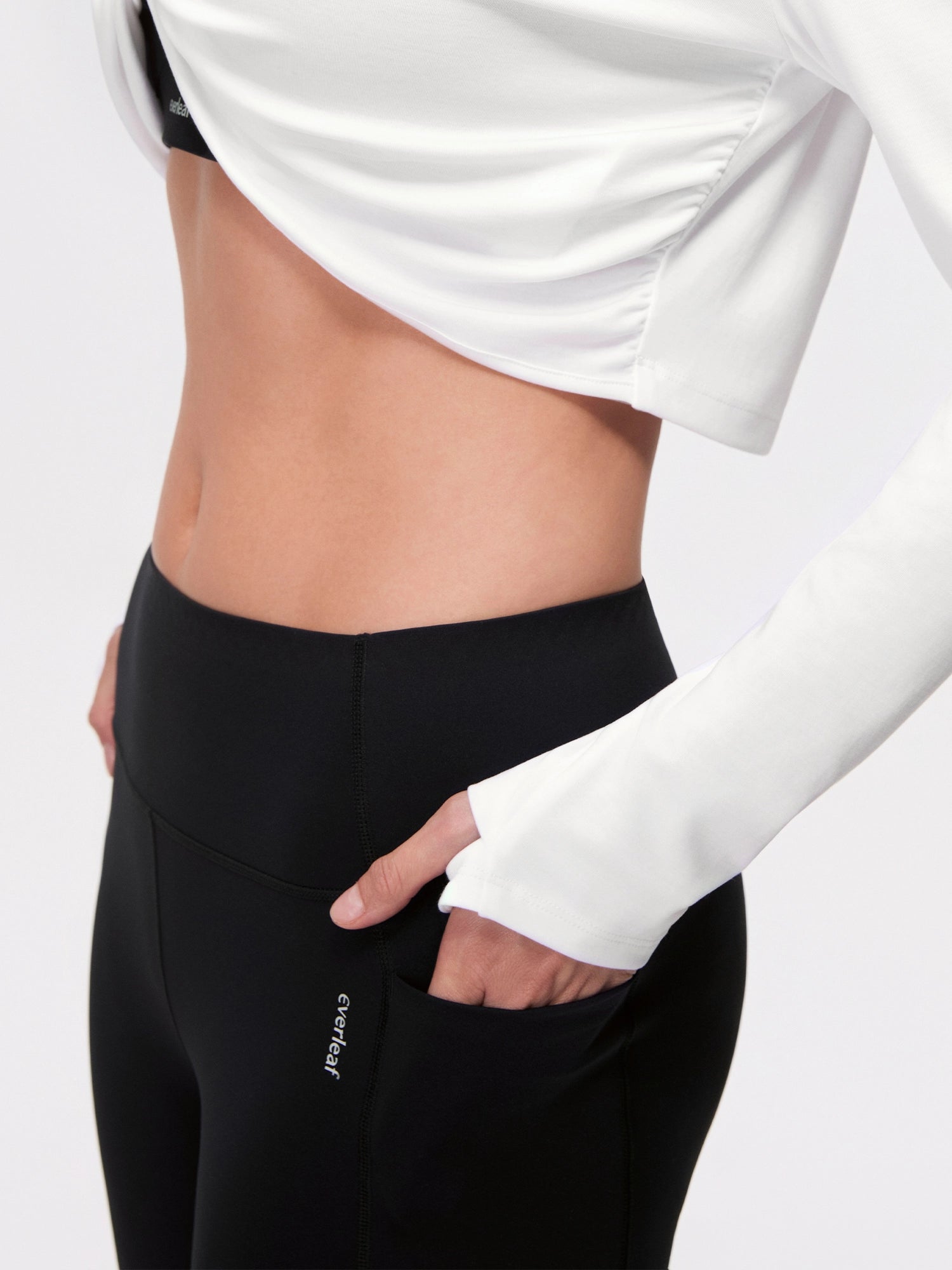 Image of Model wearing the Cloud White reversible ballet twist cardigan, thumbhole sleeve detail.