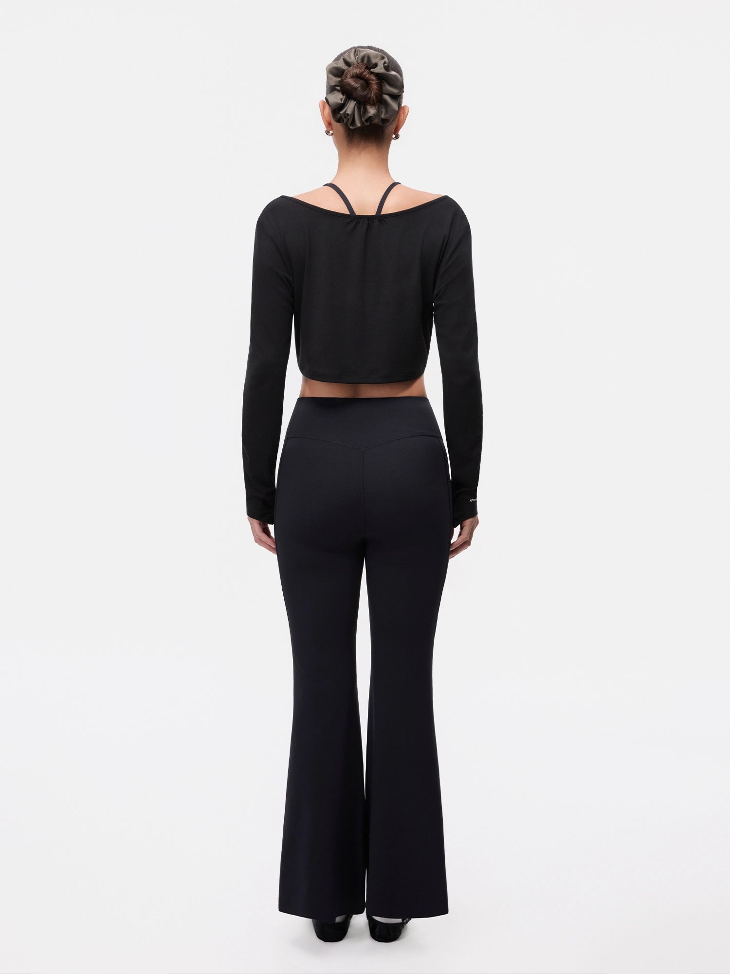 Image of Model wearing the Ebony Black Reversible Ballet Twist Cardigan, full-body back view.