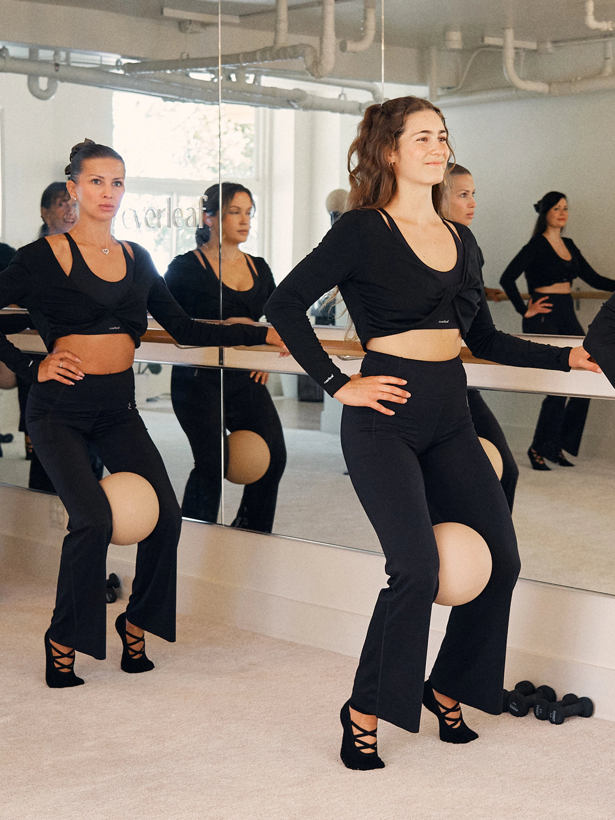 A group of people wearing Everleaf apparel practicing a barre workout with yoga balls.